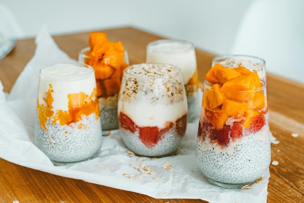 Glasses filled with chia seed pudding, yogurt, fruit, and oats as healthy no-cook meal ideas.