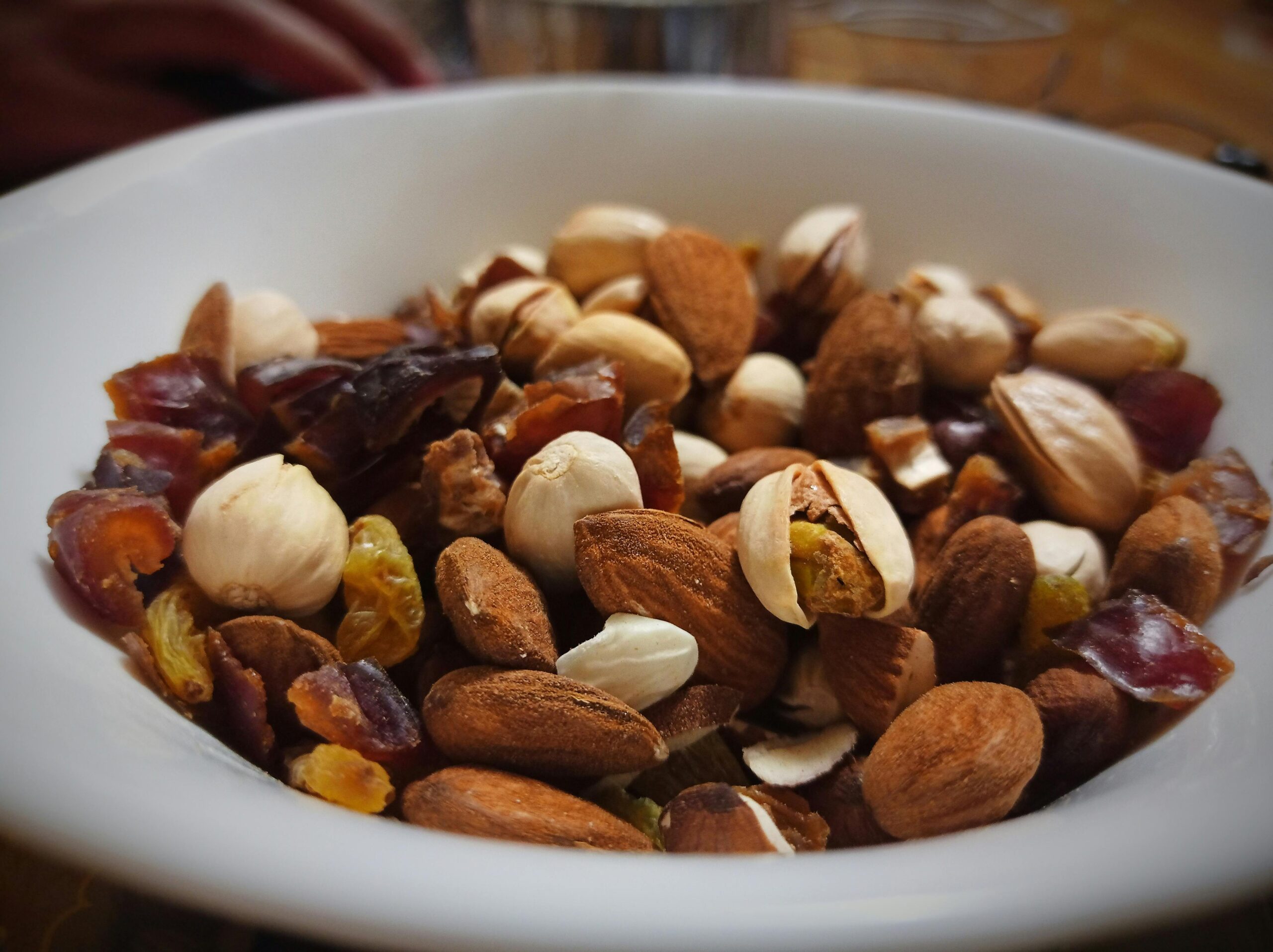 Close-up of a bowl filled with mixed nuts, dried fruit, and raisins, perfect for a homemade trail mix.
