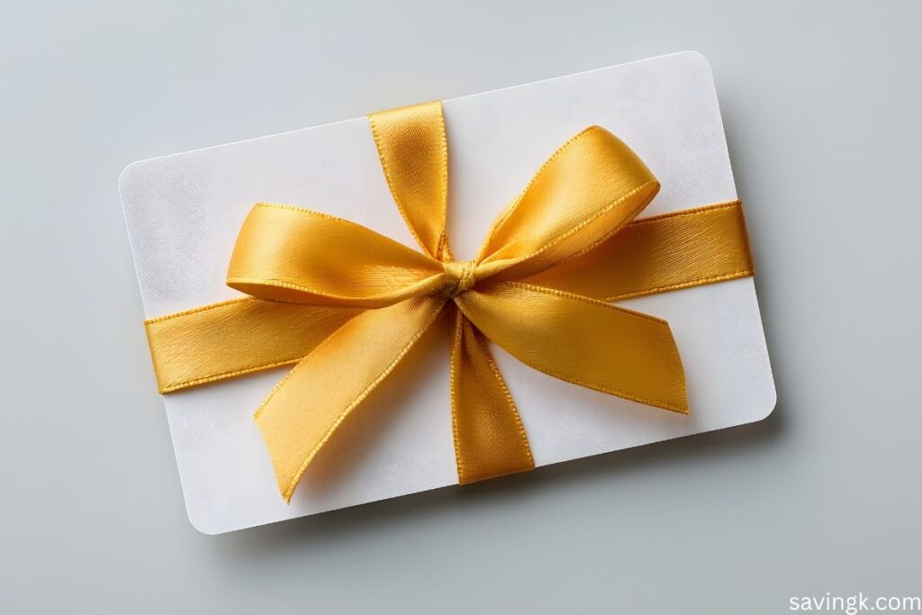 White gift card wrapped with a shiny golden ribbon bow on a light gray background.