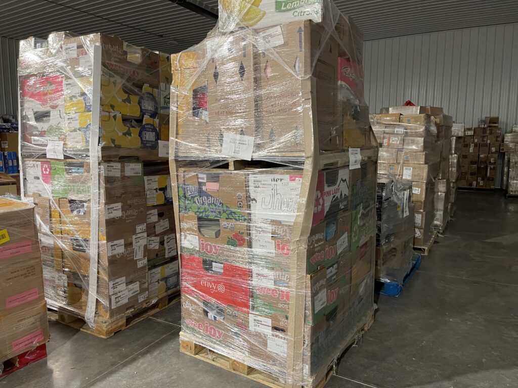 Stacks of Costco return pallets wrapped in plastic in a warehouse ready for resale.