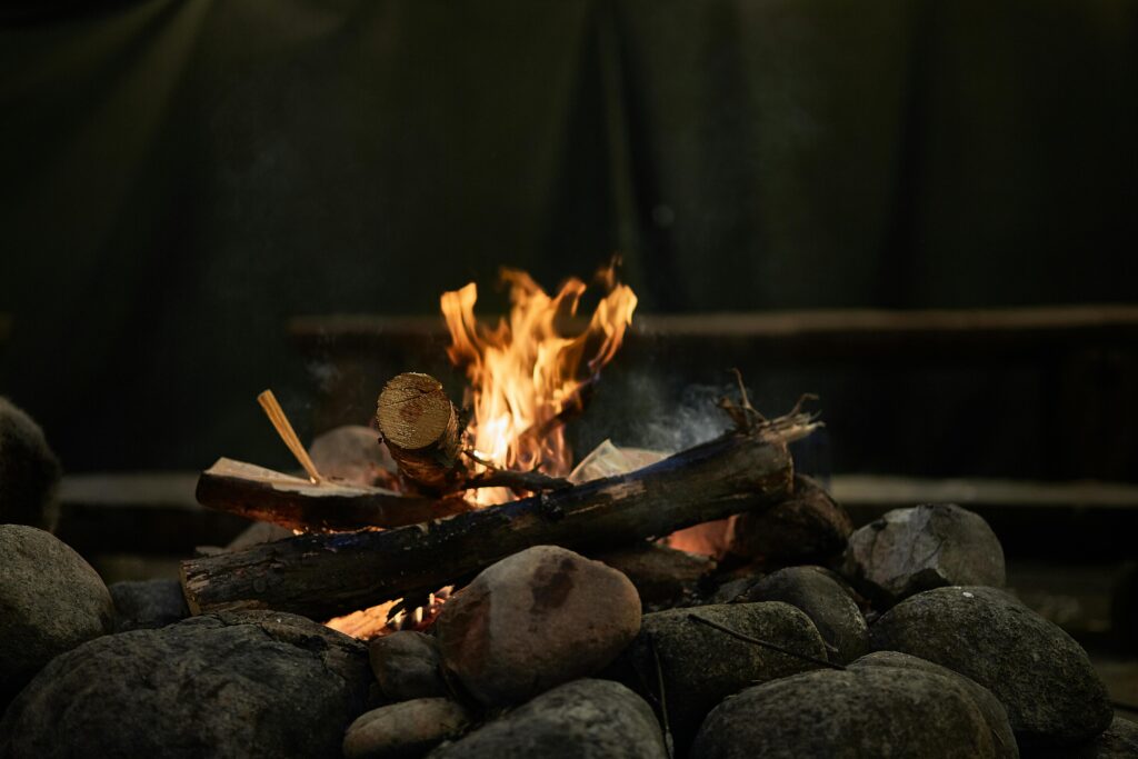 Close-up of a cozy campfire surrounded by rocks with burning logs glowing in the dark.