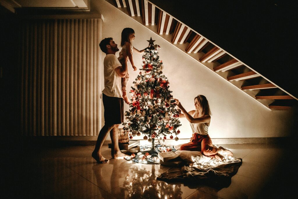 Family decorating a Christmas tree together under warm lights in their living room, creating a cozy and joyful holiday atmosphere.
