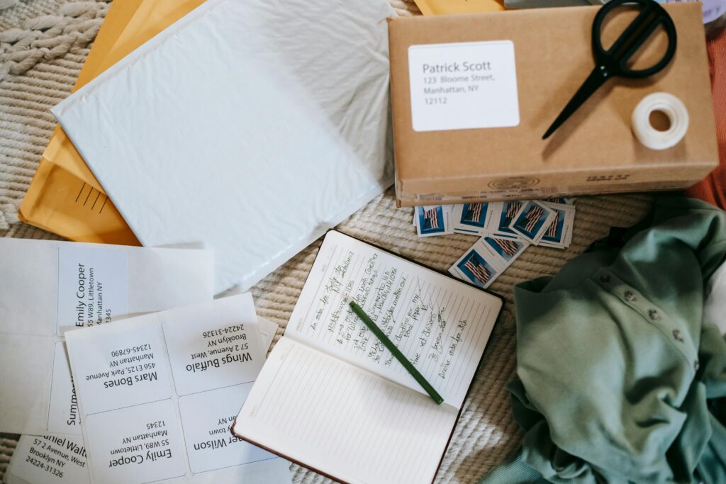 A cozy mailing setup with personalized address labels, stamps, envelopes, and a box ready to ship, showing how to stay organized with free address labels.