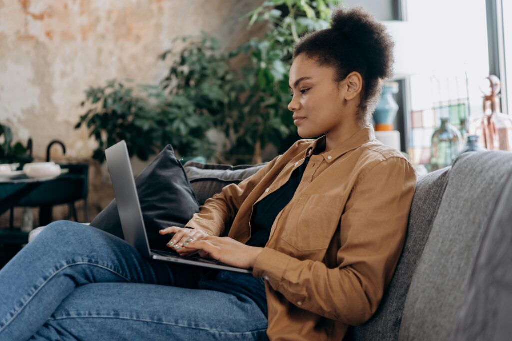 Woman sitting on a couch using a laptop to review Buy Now, Pay Later payment options.