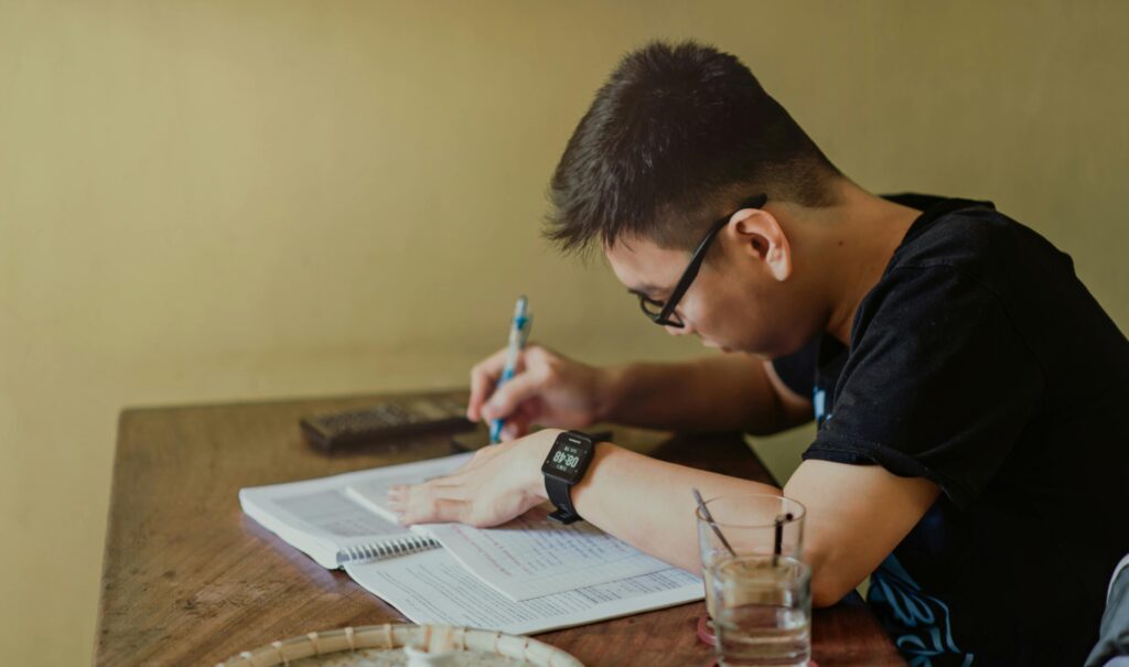 Focused student studying at a desk with notes and a laptop, representing employees taking advantage of free college programs offered by their employers.