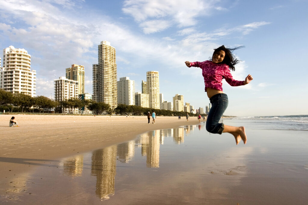 Woman jumping joyfully on a beach, symbolizing the freedom and confidence gained through a financial freedom journey.