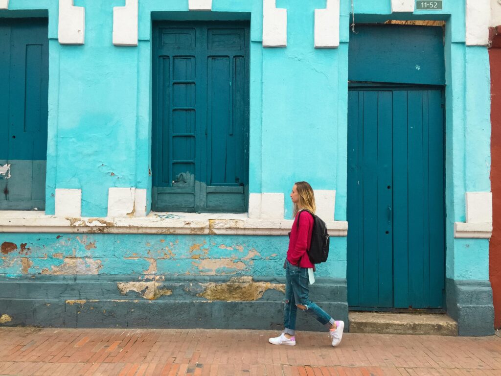 Woman walking along a colorful turquoise building, symbolizing earning money through fitness and walking apps.