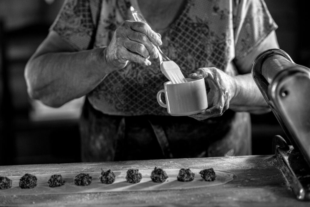 Elderly woman baking homemade treats in a rustic kitchen, symbolizing traditional money-saving habits like cooking from scratch.