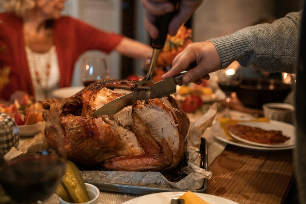 Carving a roasted Thanksgiving turkey at a family dinner table.