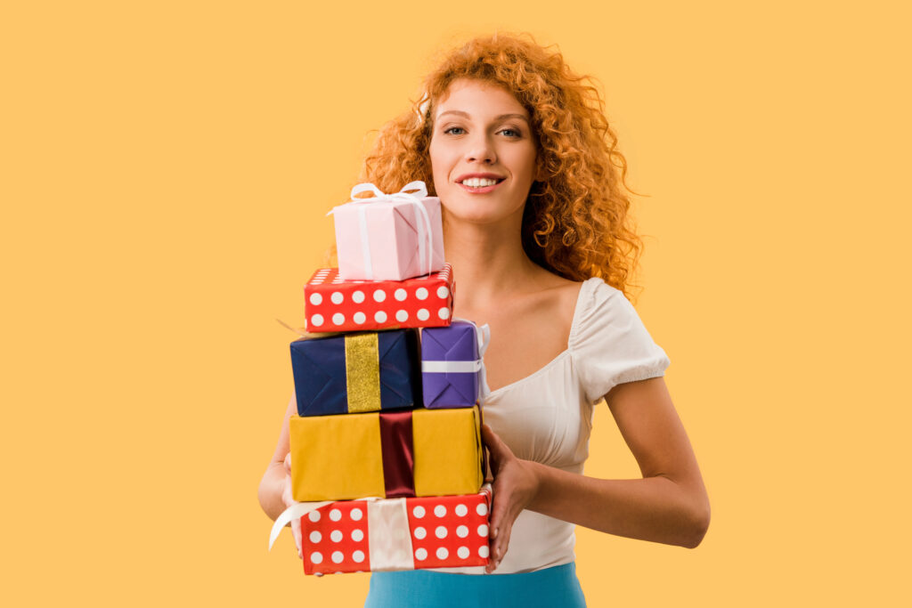 Woman holding a stack of colorful wrapped gifts representing free gift catalogs and gift ideas by mail