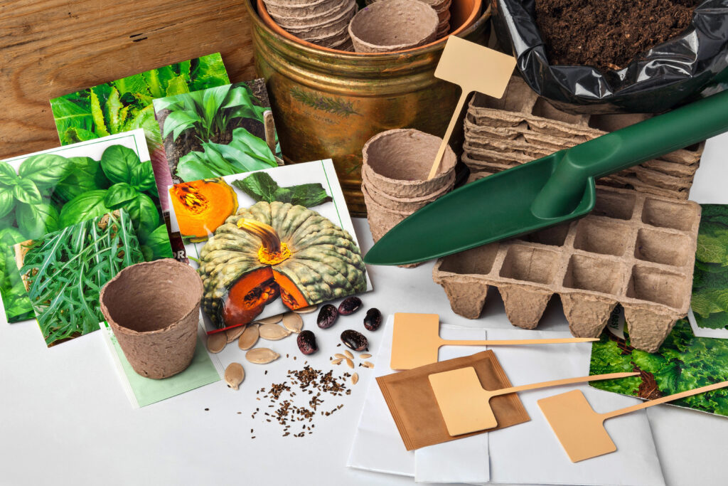 Free seed catalogs with gardening supplies including seed packets, biodegradable pots, planting trays, and hand tools on a white background