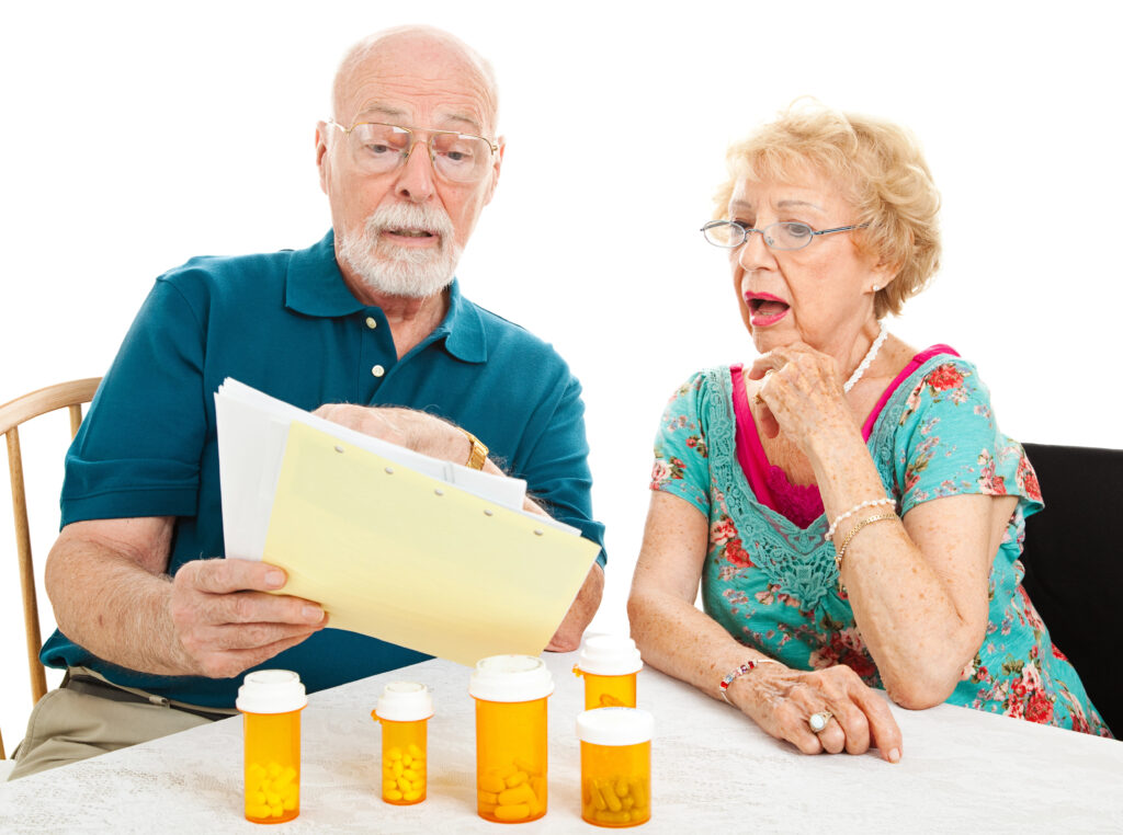 Older couple reviewing medical bills and prescription costs, surprised by unexpected Medicare expenses.