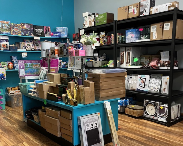 Liquidation store shelves filled with discounted products including toys, home goods, electronics, and boxed inventory ready for resale