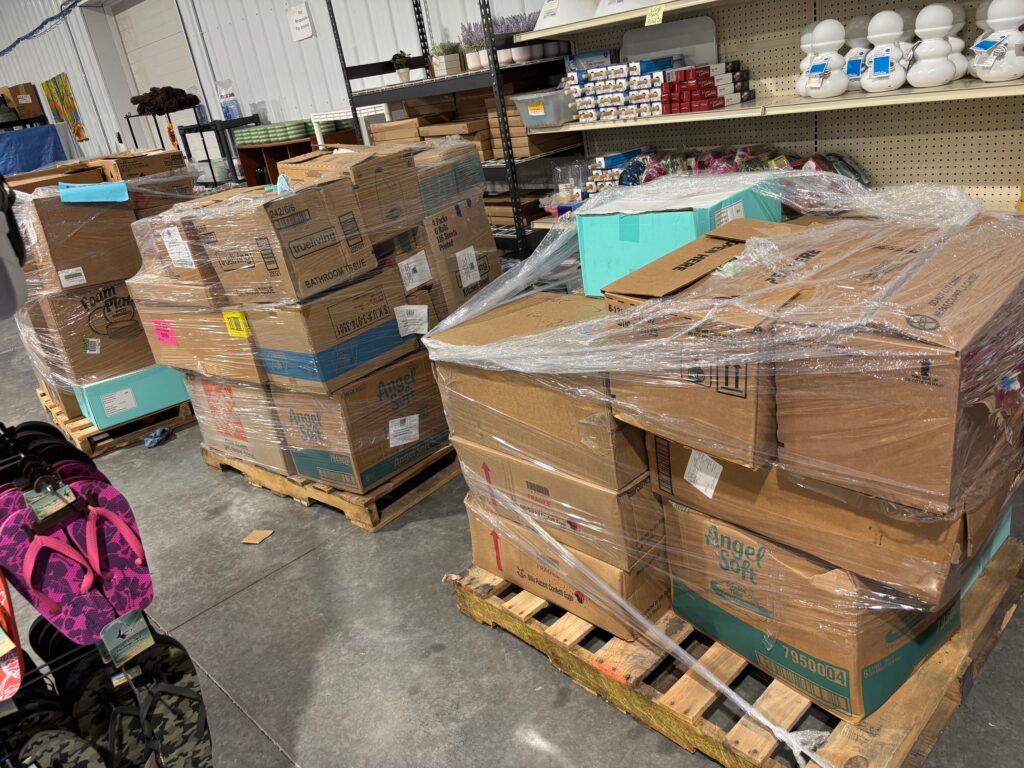 Liquidation pallets wrapped in plastic with mixed inventory boxes in a warehouse, showing bulk merchandise for resale