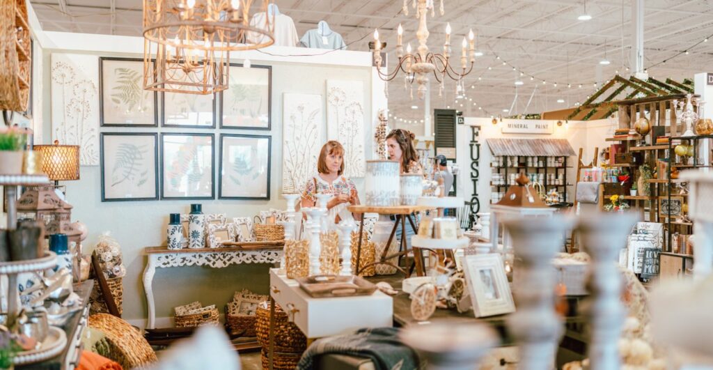 Vendor booth inside a boutique-style market with home decor, framed art, and lighting displays