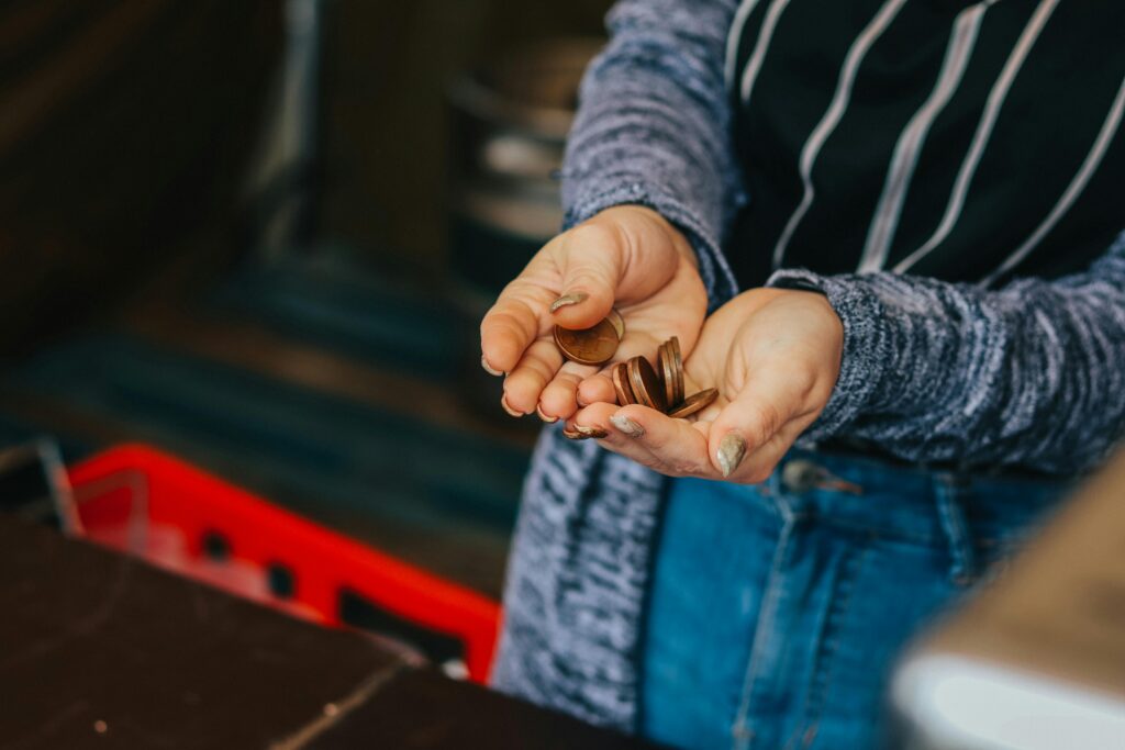 Person holding a handful of coins while counting change at a counter