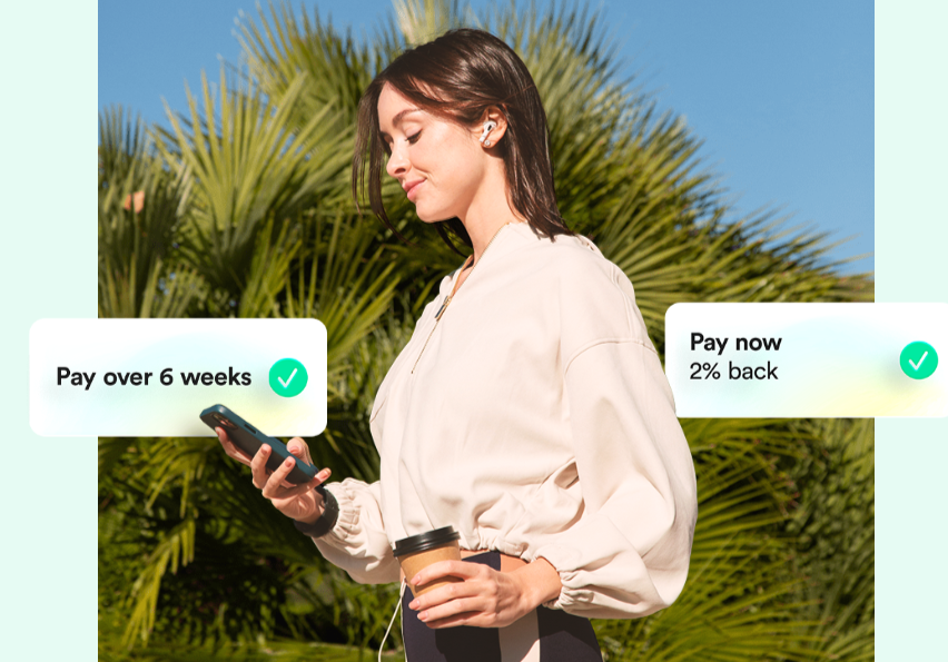 Woman holding a phone and coffee outdoors with Zilch buy now pay later payment options displayed on screen