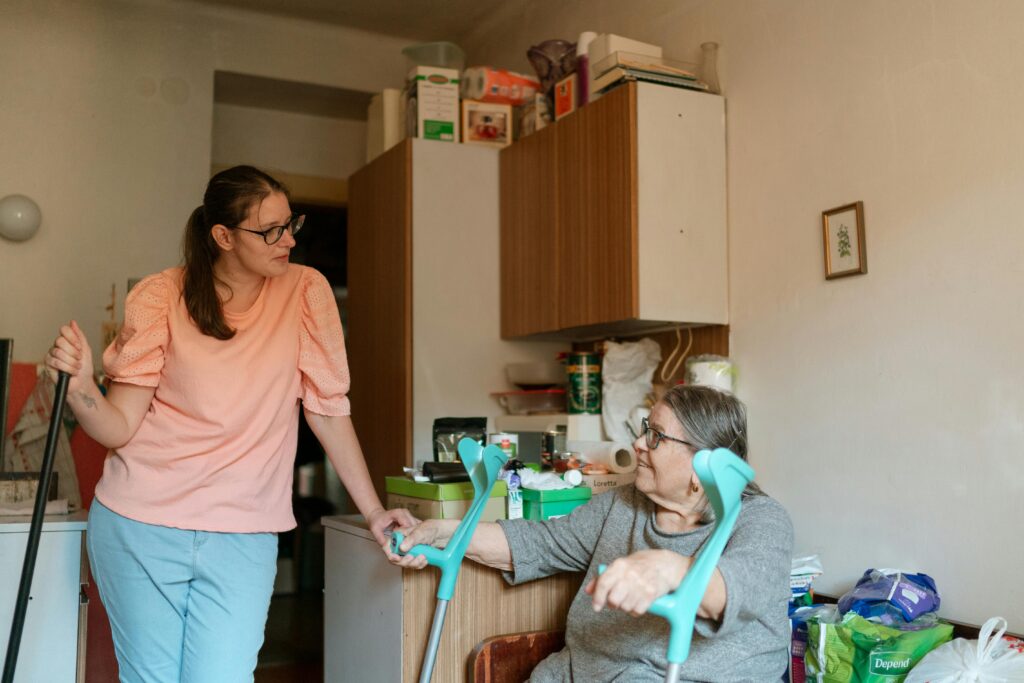 Woman helping an elderly family member at home while discussing mobility assistance and caregiving support.