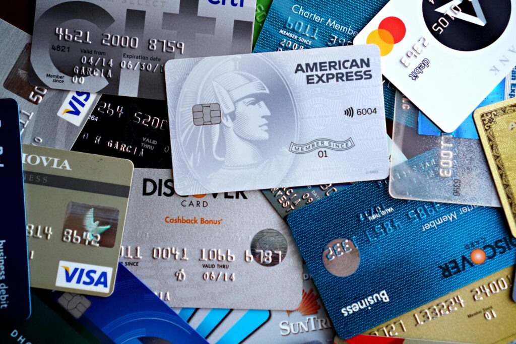 Assorted credit cards including an American Express card displayed in a pile of payment cards