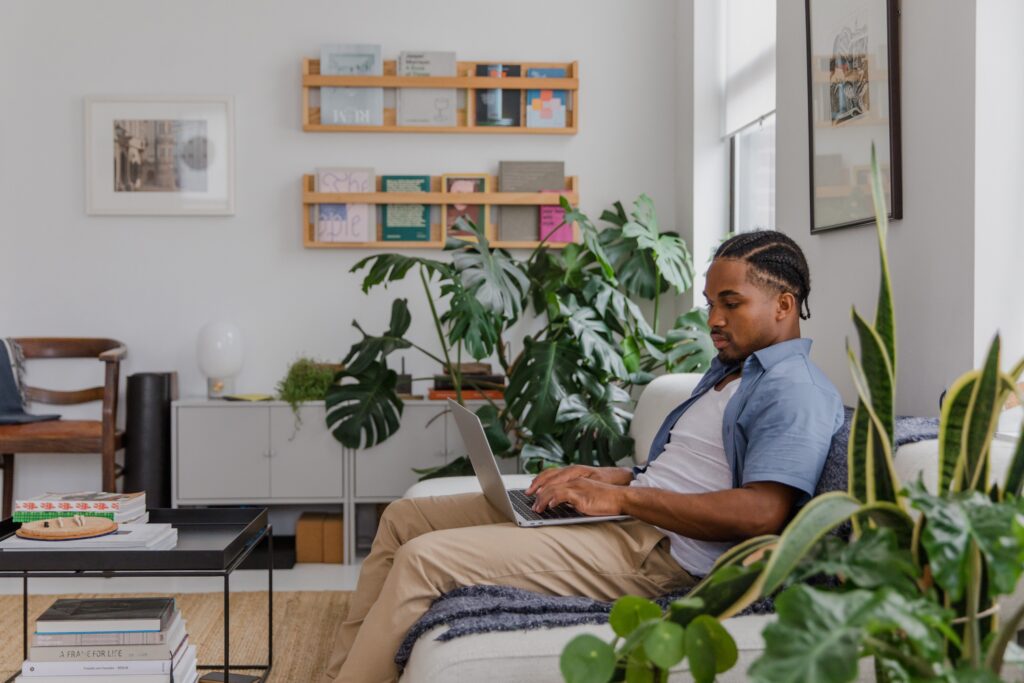 Person working on a laptop from a cozy home office surrounded by houseplants, researching finance newsletters and online financial content.