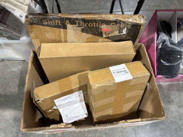 A box filled with unopened undeliverable shipping packages waiting to be sorted and opened by a reseller.