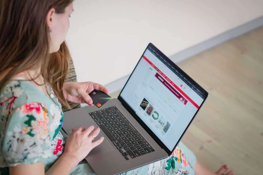Woman holding a credit card while shopping online on a laptop, illustrating online purchases with money-back guarantees.