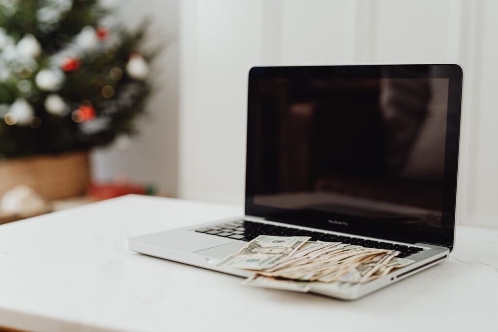 a laptop on a desk covered with cash