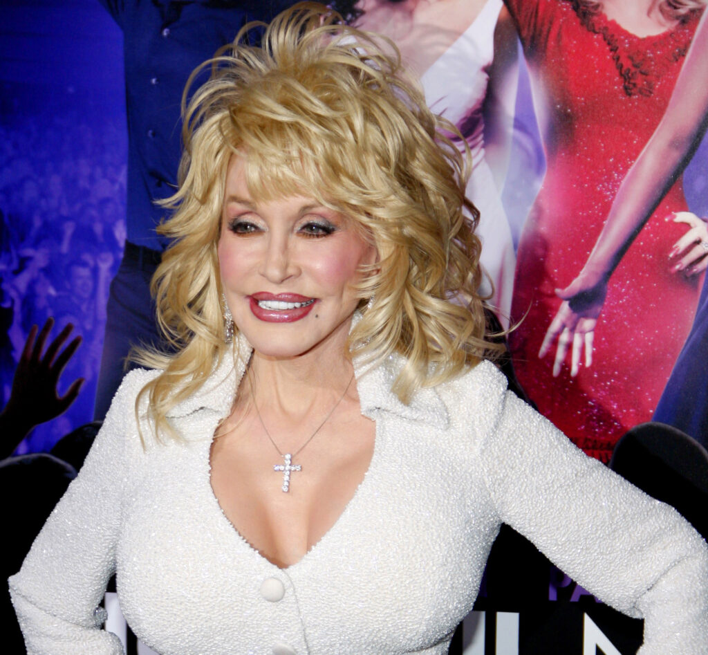Dolly Parton smiling at an event, featured in a tribute about money lessons from her life and career.