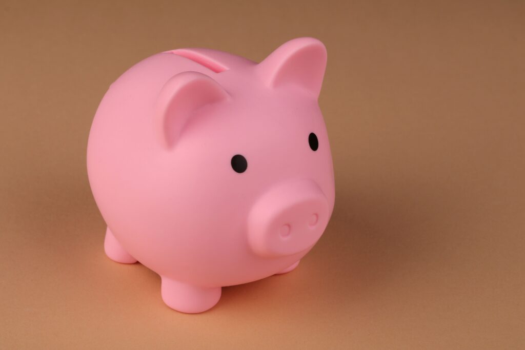 Pink piggy bank on a brown background representing credit piggybacking and building credit.
