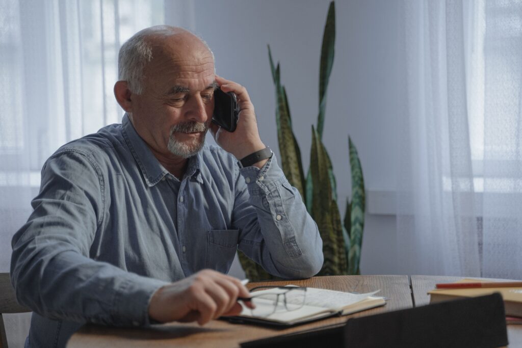 Man over 50 working from home while talking on the phone