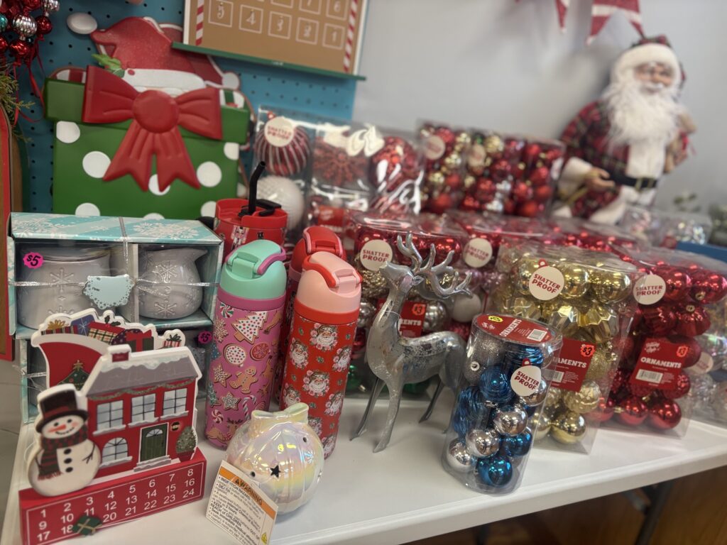 Christmas liquidation merchandise featuring discounted ornaments, holiday decorations, festive tumblers, and Christmas decor displayed in a retail store.