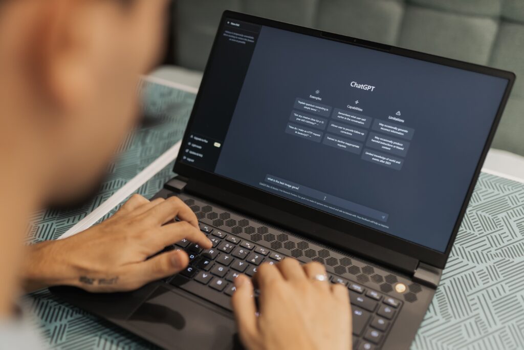 Person typing on a laptop displaying ChatGPT, illustrating ways to make money with AI and online side hustles.