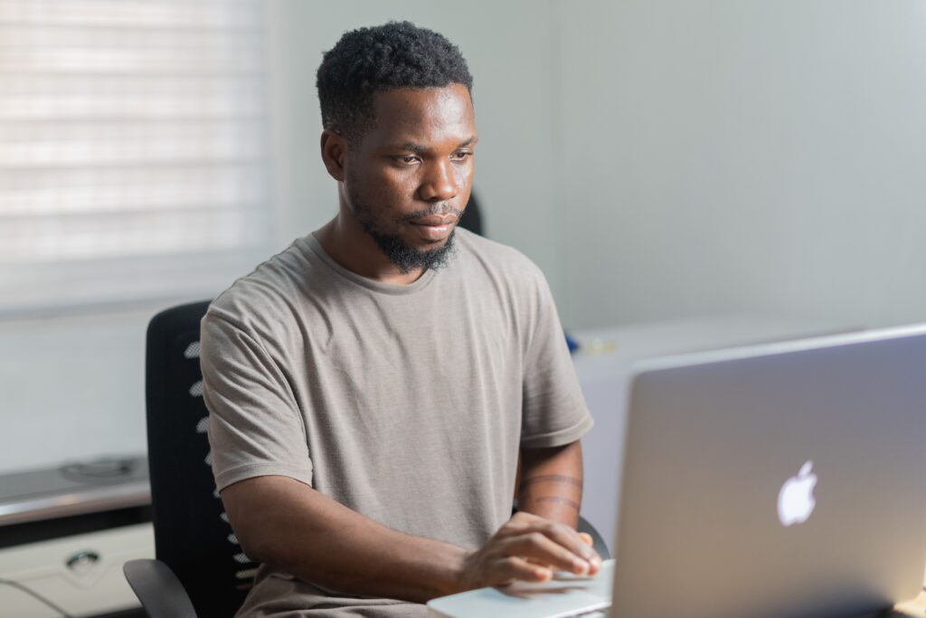 Man sitting at a desk using a laptop to research online investing and copy trading strategies.