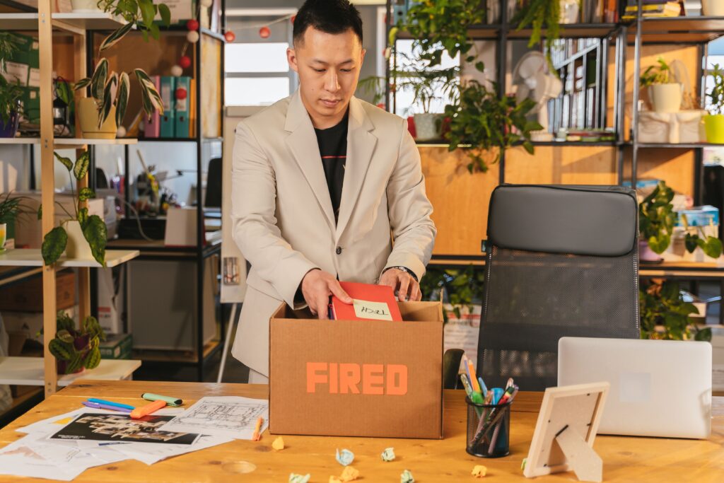 Man packing his belongings into a cardboard box after being fired from his job, illustrating how job loss can inspire a new business venture.