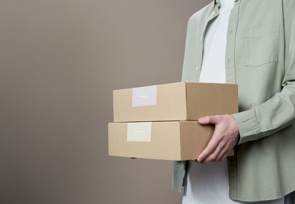 Person holding two cardboard shipping boxes, representing online reselling and using AI to find profitable products.